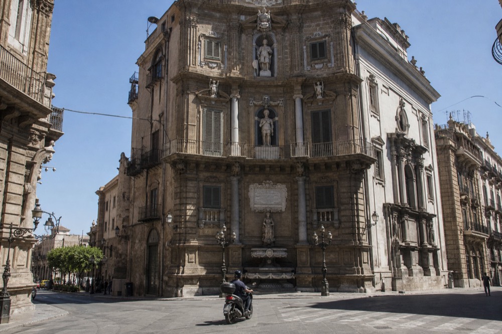 An ornate baroque church facade on a Palermo street under a clear sky