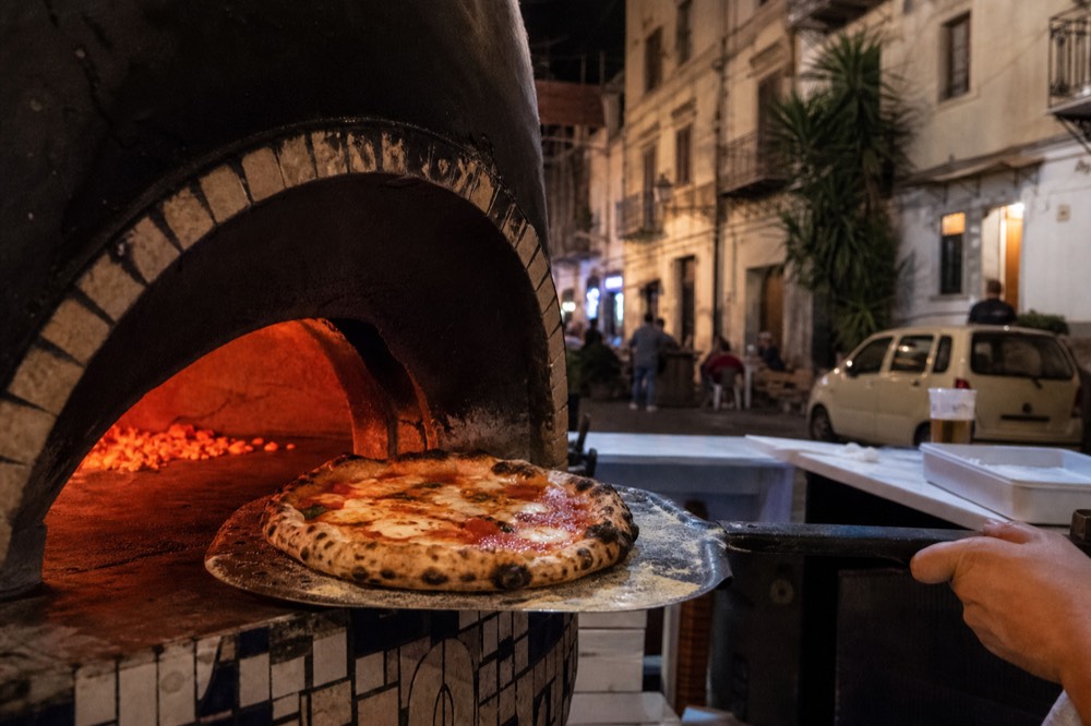 A round pizza fresh from the oven in a Palermo pizzeria