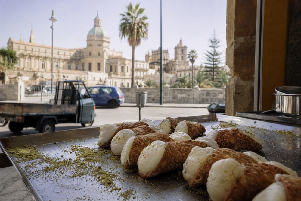 Cannoli shells filled with ricotta cream arranged on a pastry counter