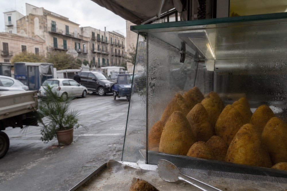 Golden fried arancine stacked in a friggitoria display case