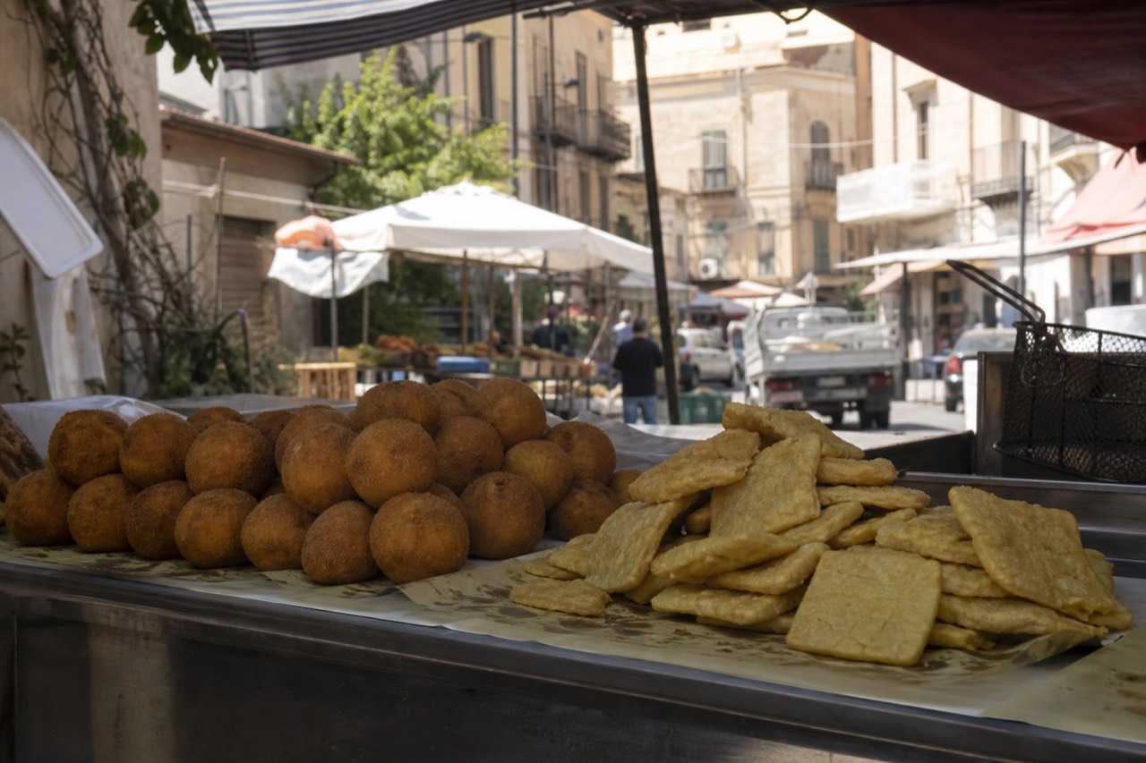 Fried arancine and panelle stacked on a Sicilian market counter