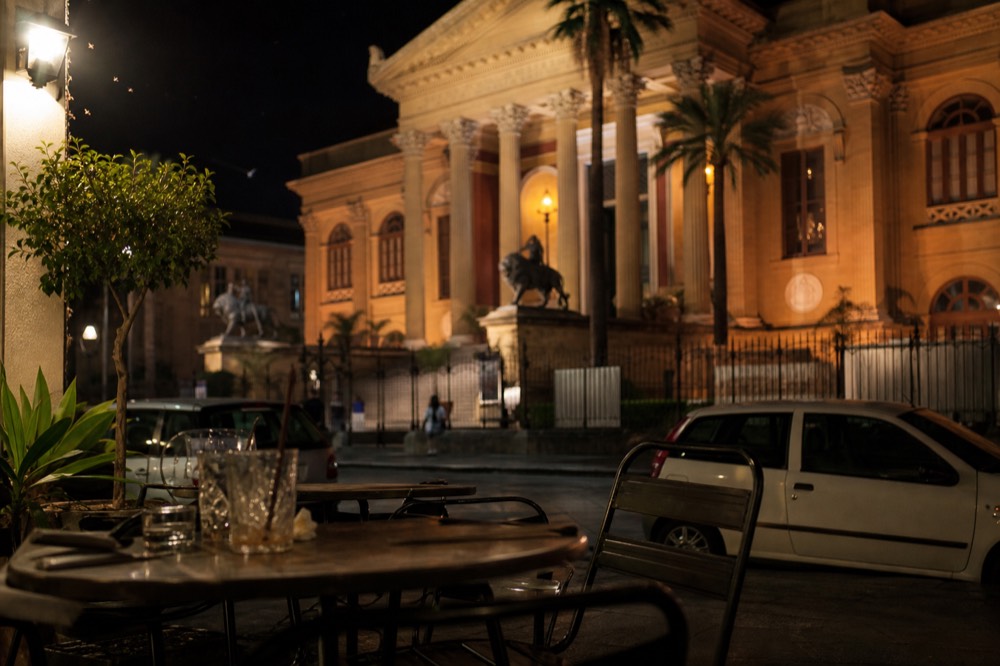 Evening cafe terrace near Teatro Massimo with lit theatre facade in the background