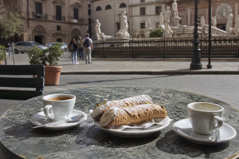 Cannoli and small cups of espresso arranged on a café table