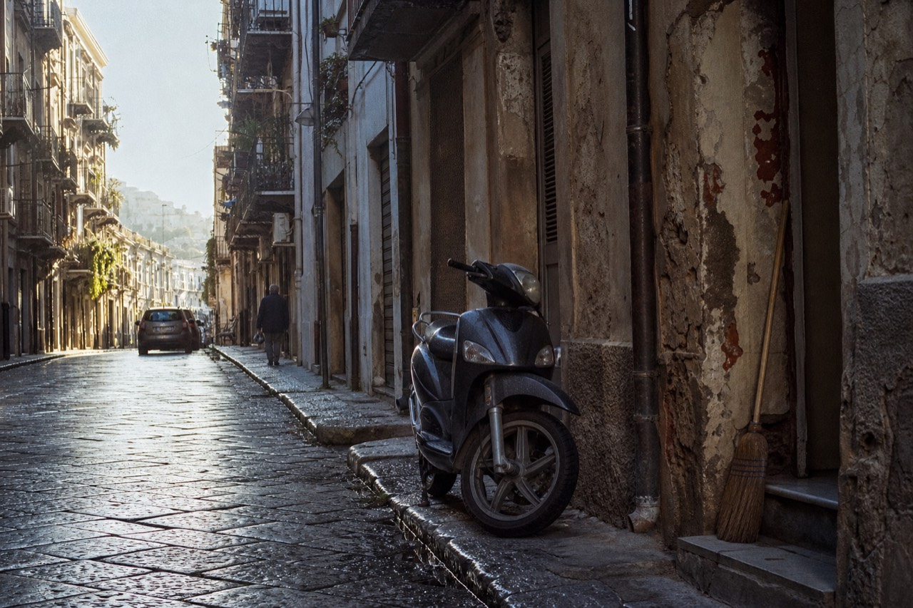 A Palermo street in morning light with worn stone facades and closed wooden shutters