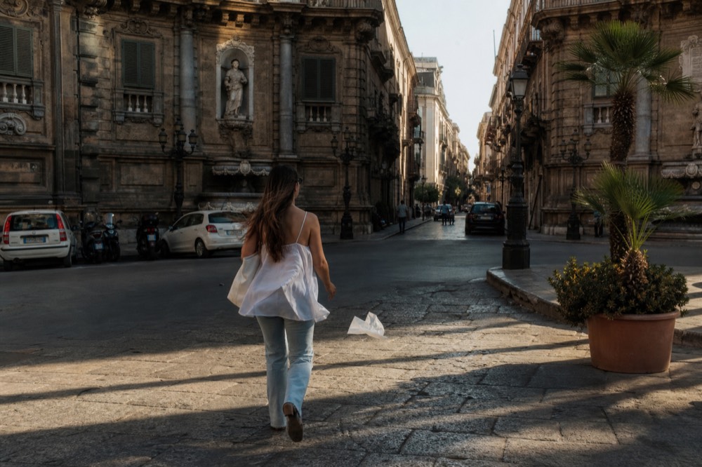 A sunlit Palermo street with warm stone buildings and long shadows
