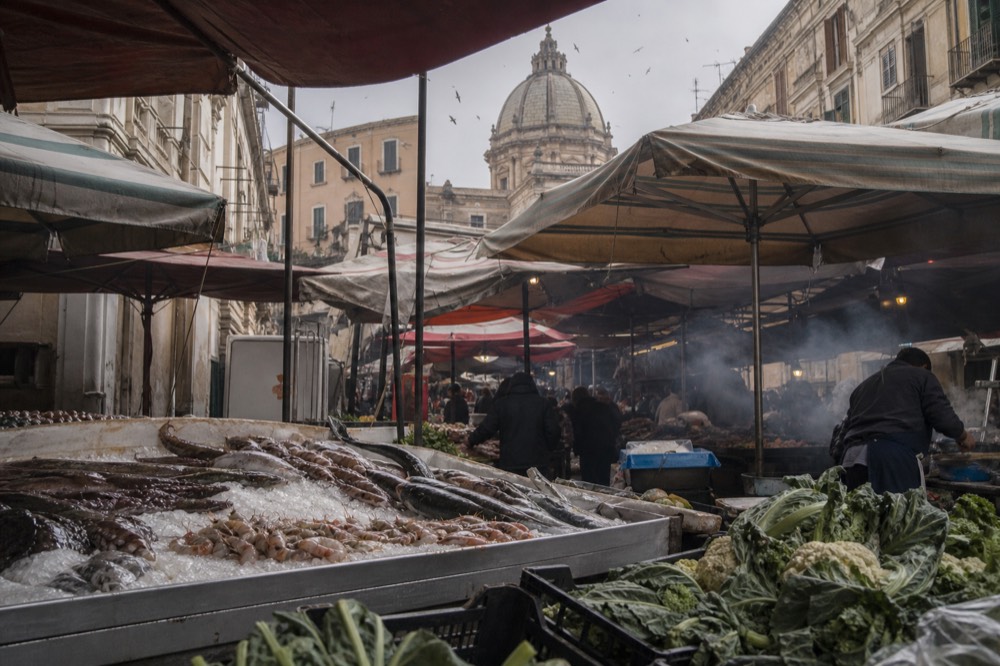 Fish and produce stalls crowded together in the Ballarò market