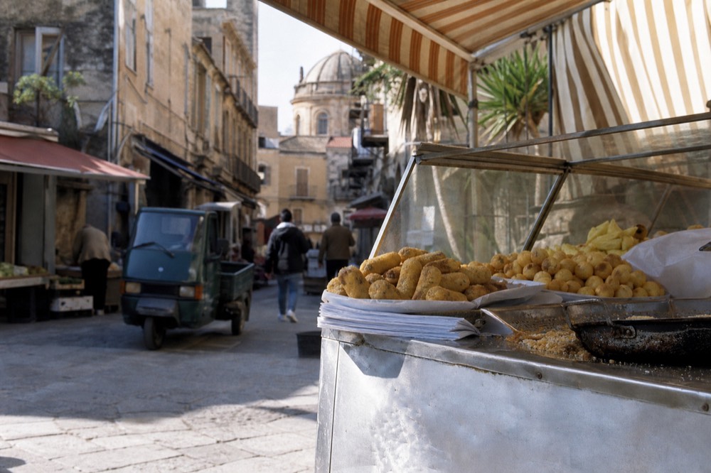 A market stall counter with fried snacks and stacked paper trays