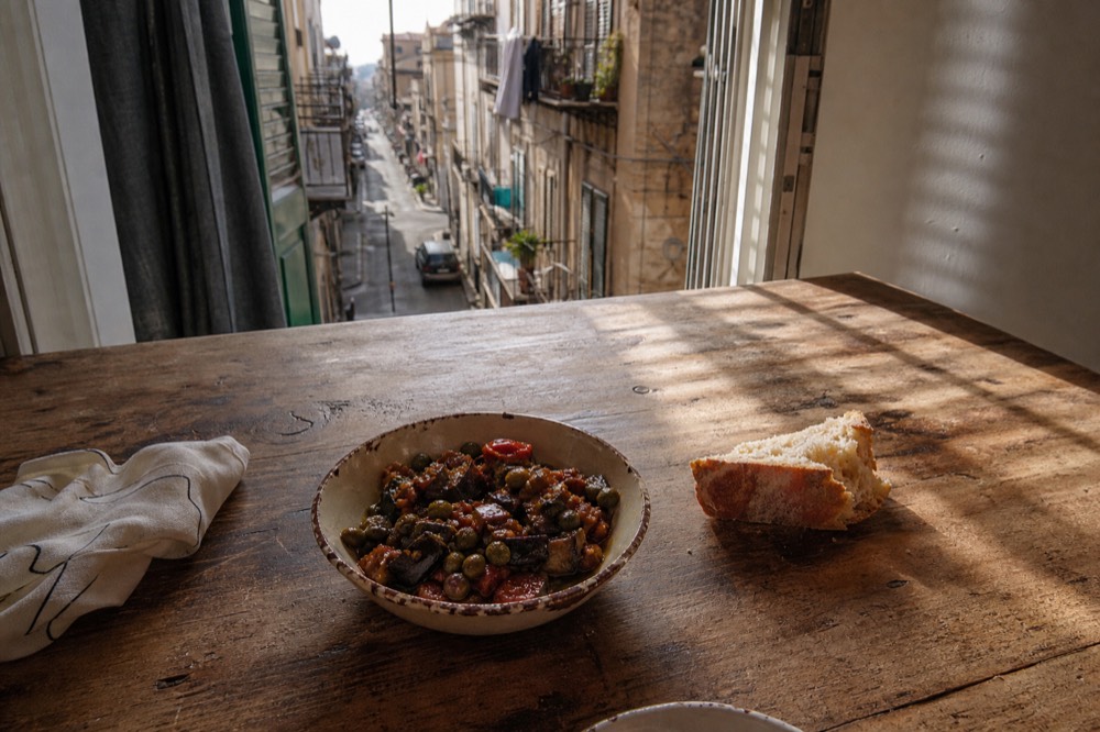 Fried aubergine caponata in a ceramic bowl on a wooden table