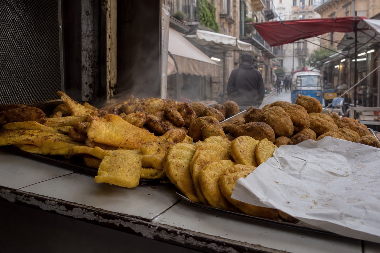 Fried chickpea fritters and rice balls on a market counter in Palermo