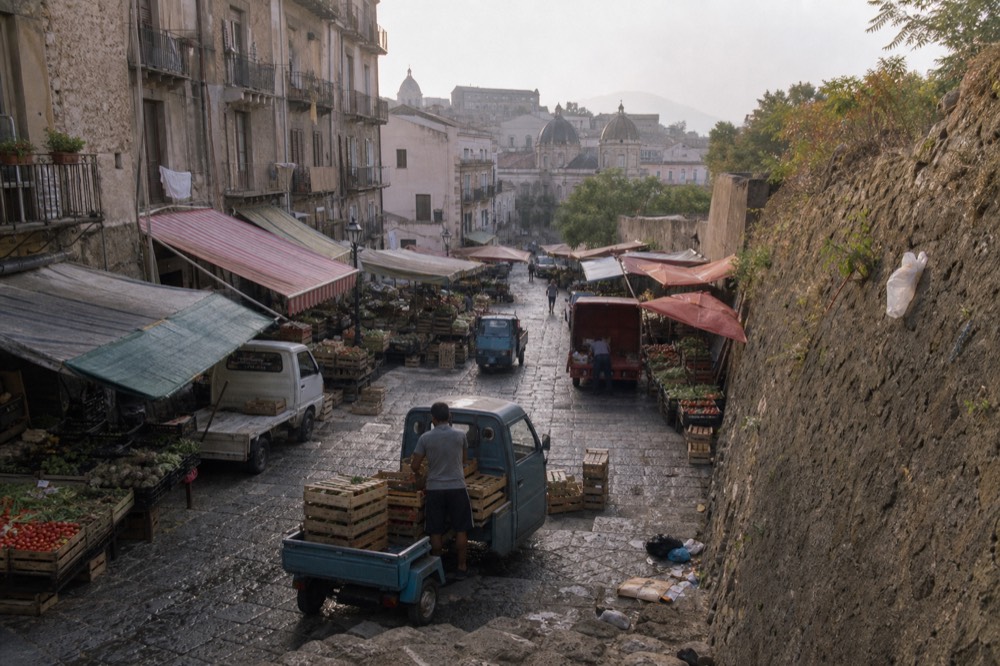 A Palermo market street in early morning with stalls of vegetables and crates being unloaded