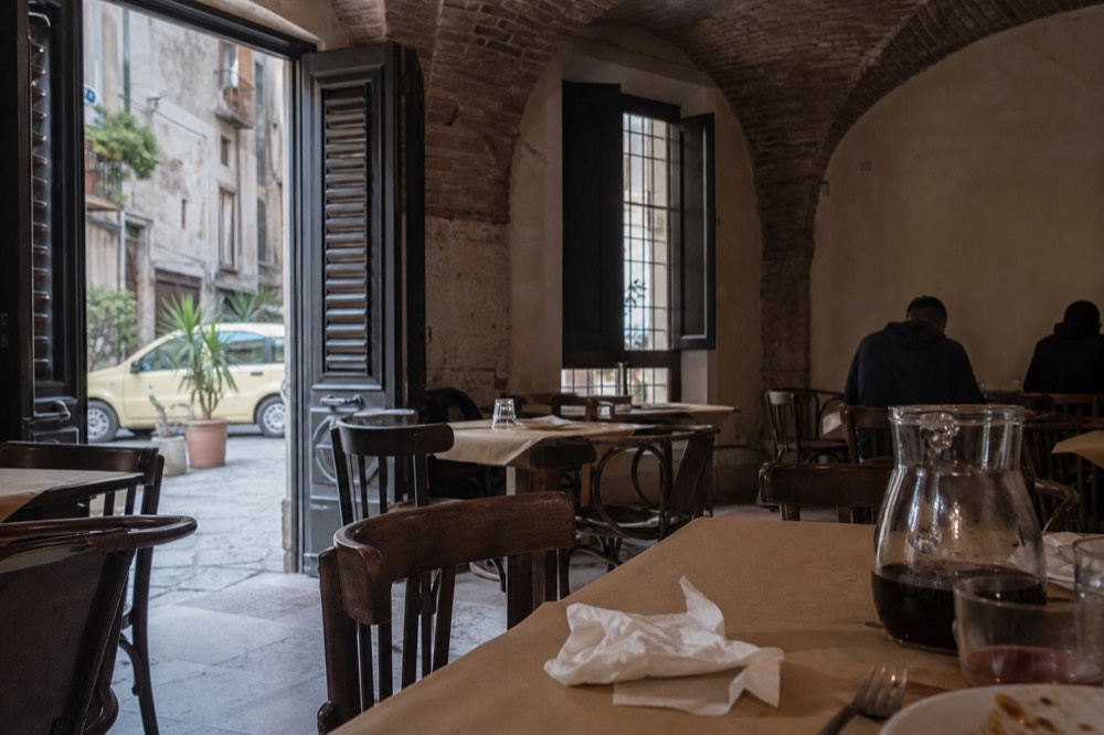 A simple Palermo trattoria dining room with paper-covered tables and chairs