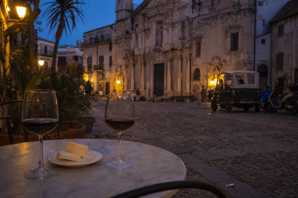 Glasses of red wine and a plate of cheese on a small marble bar table